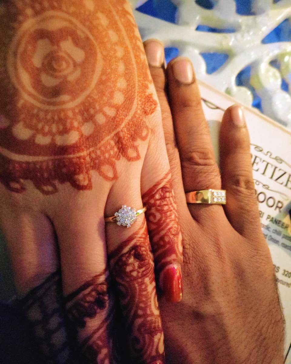 Couple holding hands showing a diamond engagement ring and gold wedding band