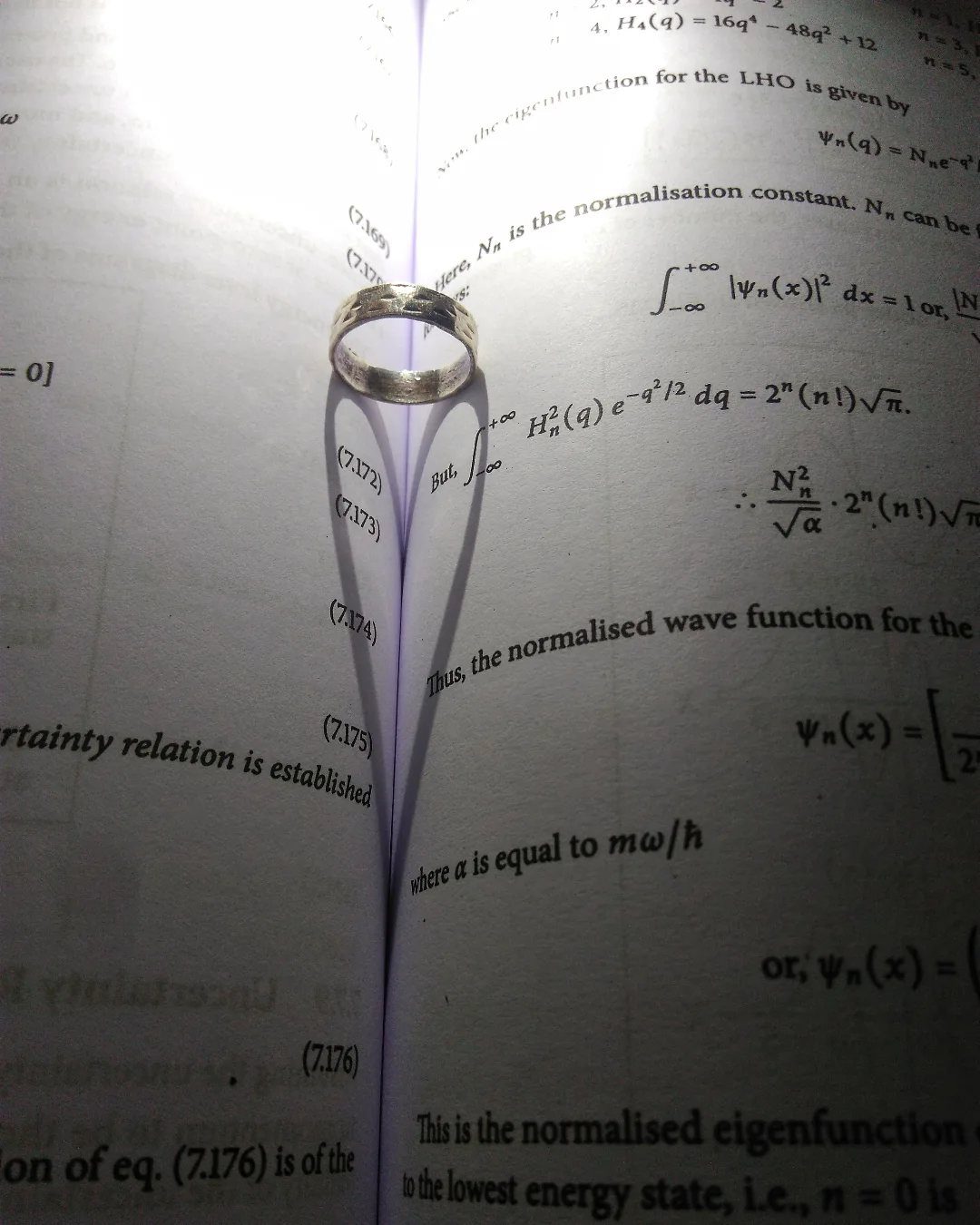Silver ring resting on the center fold of an open physics textbook
