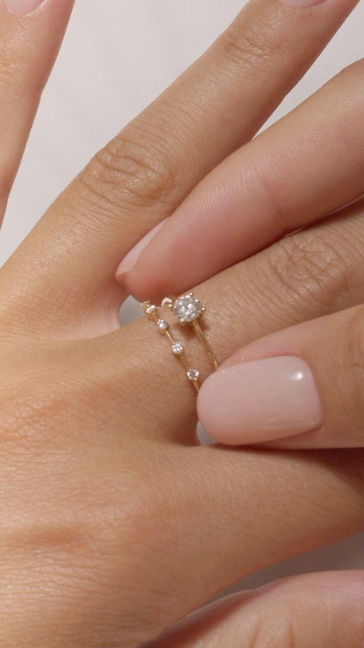 Gold engagement ring with a single diamond paired with a thin diamond band.