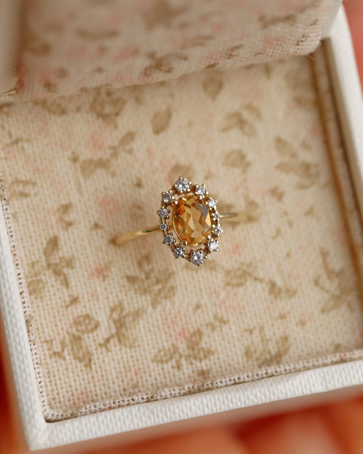Gold ring with oval yellow citrine and diamond halo in floral jewelry box