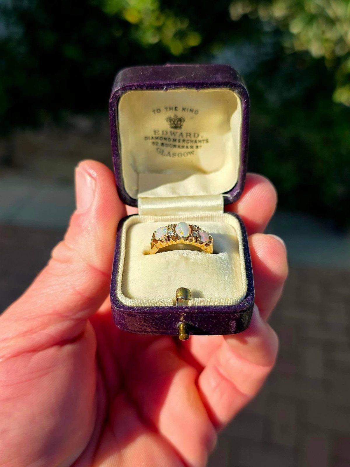 Gold ring with three white stones in a purple velvet jewelry box