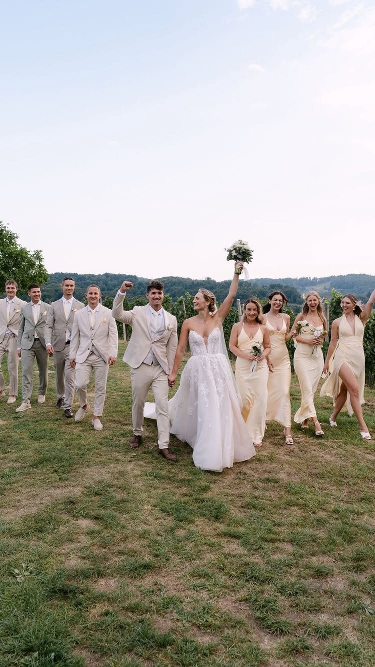 Wedding party walking in a field wearing coordinating beige and champagne outfits.