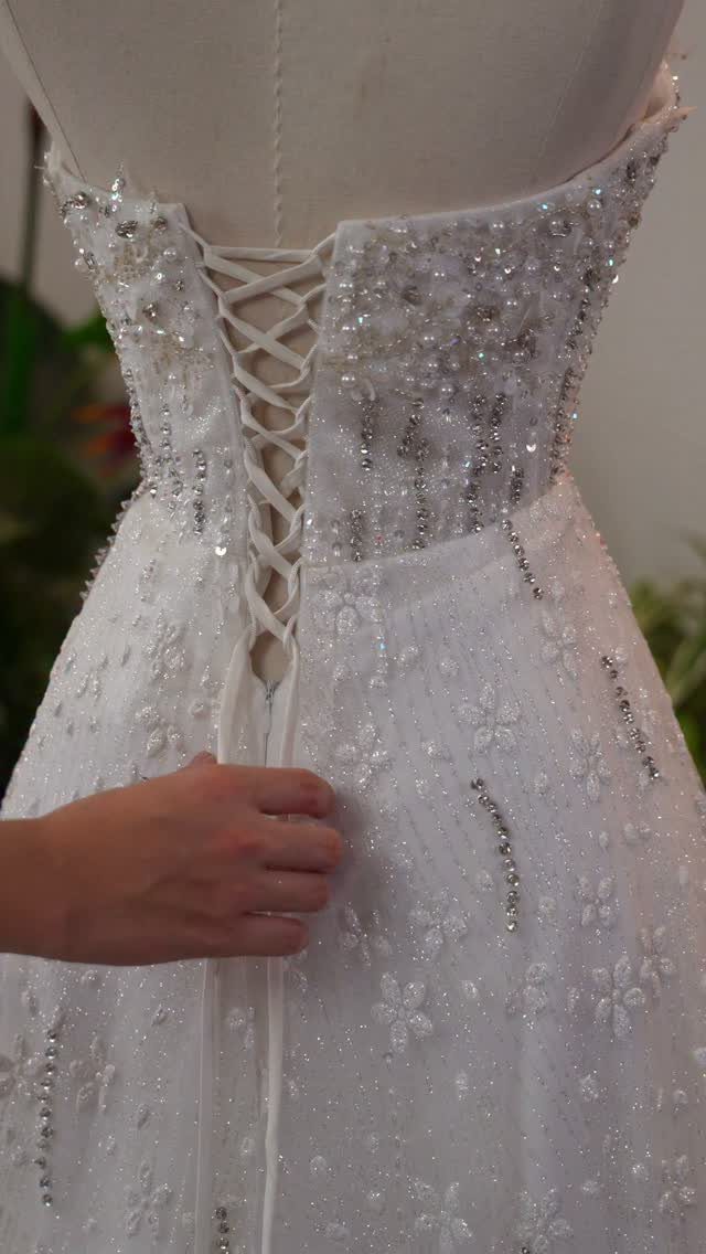 White beaded wedding dress with a lace-up corset back on a mannequin