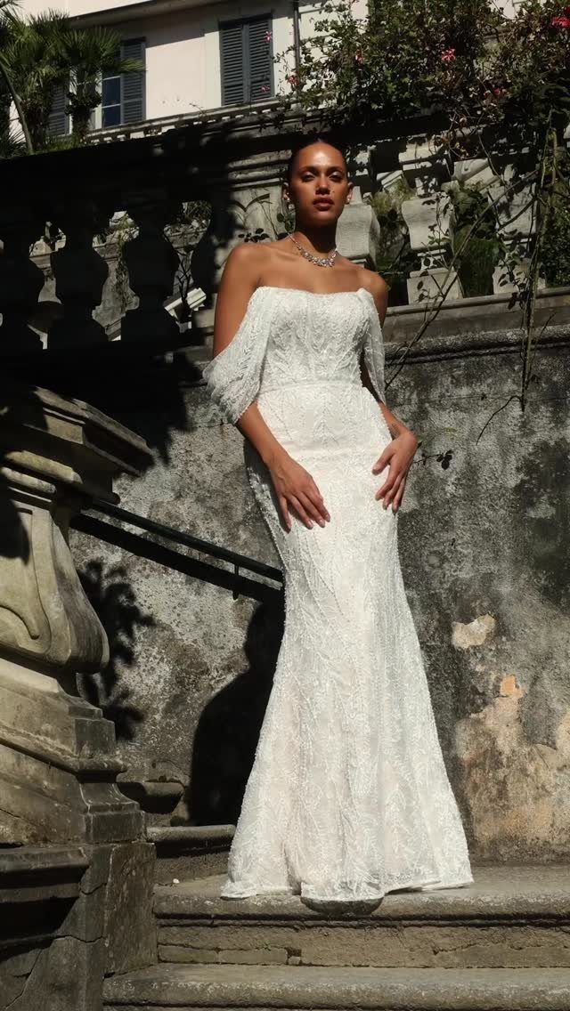 Woman in a white beaded lace wedding dress standing on stone steps.