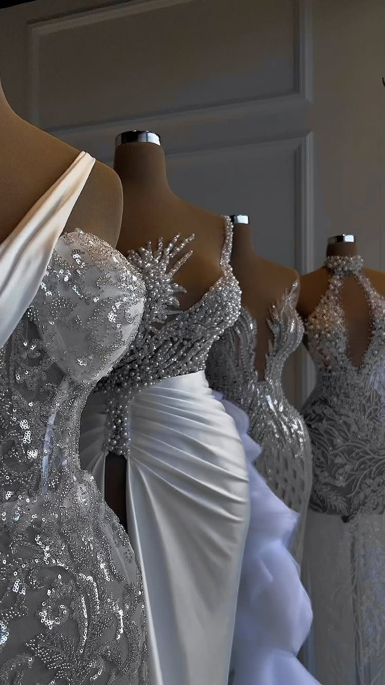 White and silver beaded wedding dresses displayed on mannequins in a bright room.