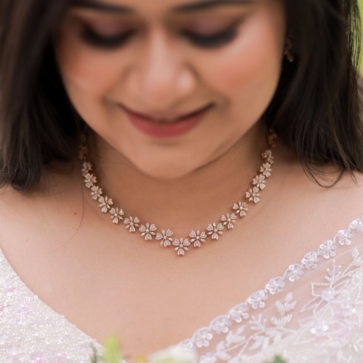 Rose gold floral diamond necklace worn with a white lace bridal dress