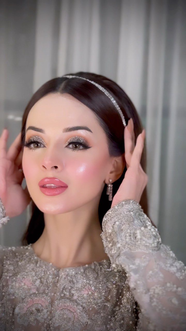 Woman in a sparkling white embellished dress wearing a headband and dangling earrings.