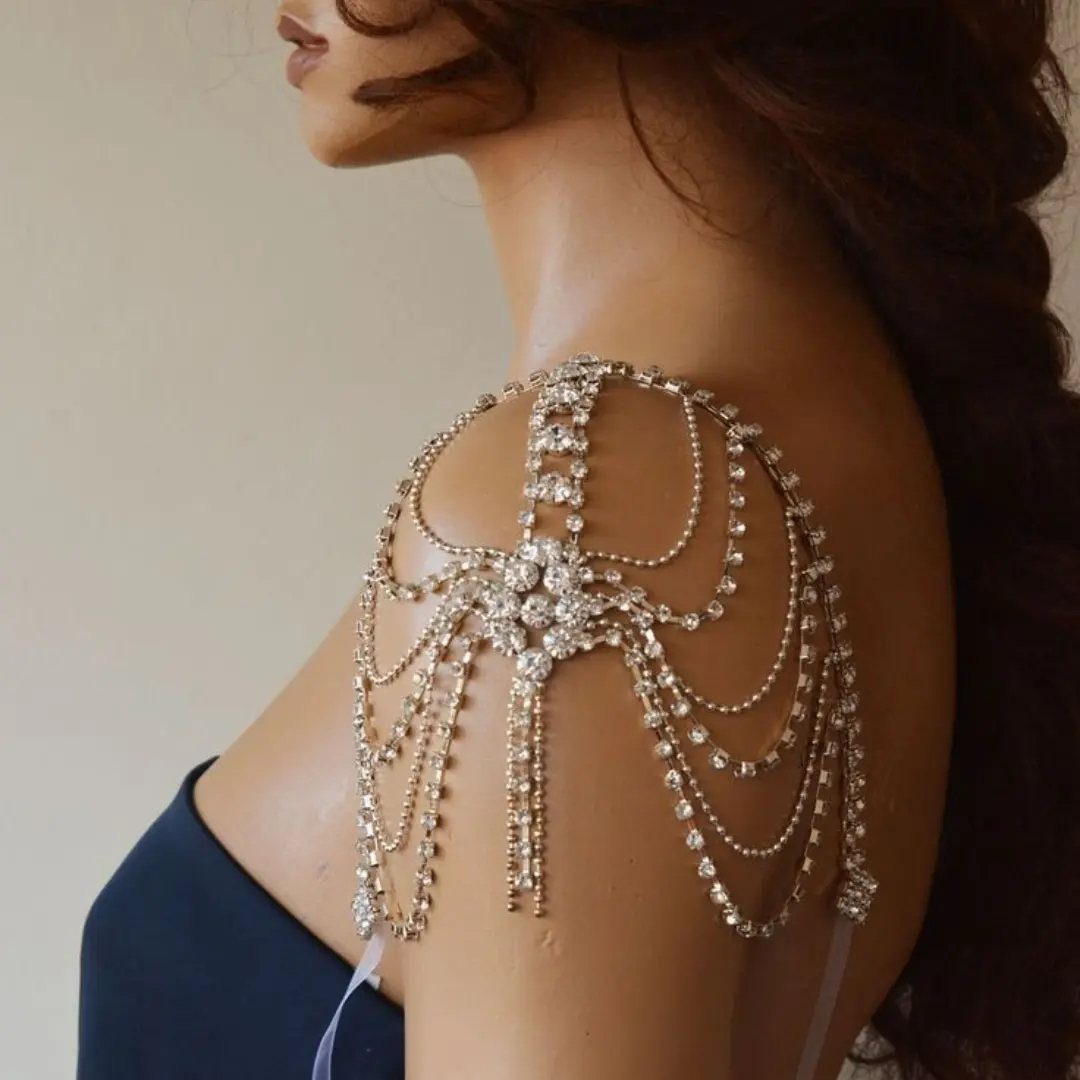 Crystal body chain draping over a shoulder and arm with blue dress