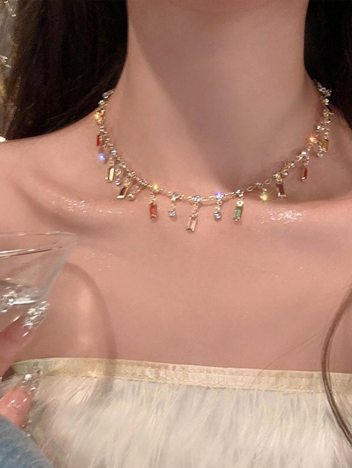 Gold choker necklace with colorful gemstones worn with a white off-shoulder dress