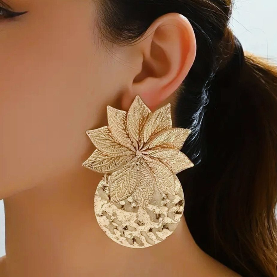 Large gold statement earring with a floral design and hammered circular disc.
