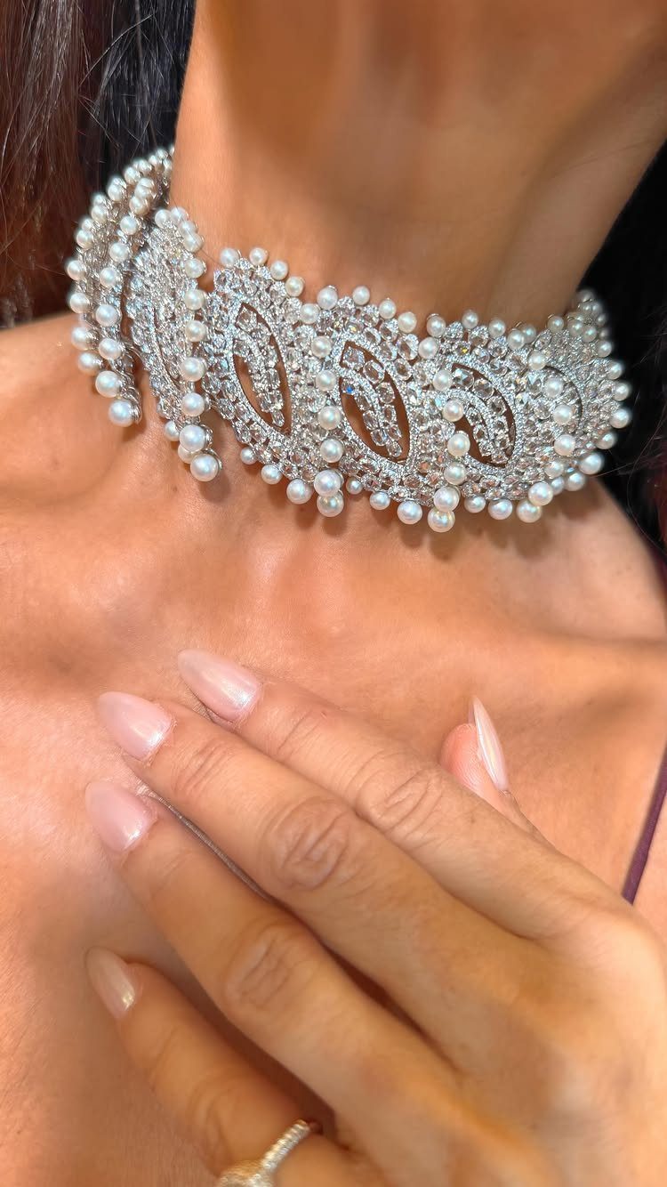 Ornate silver choker necklace with crystals and pearls worn on a person's neck.