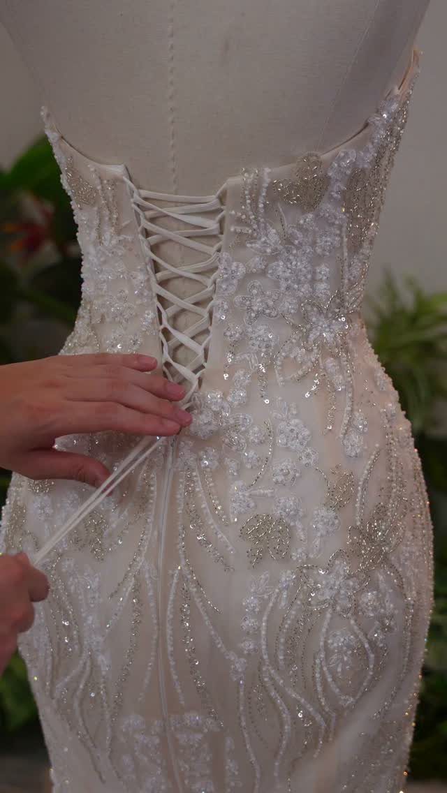 White beaded wedding dress on a mannequin with a lace-up corset back.