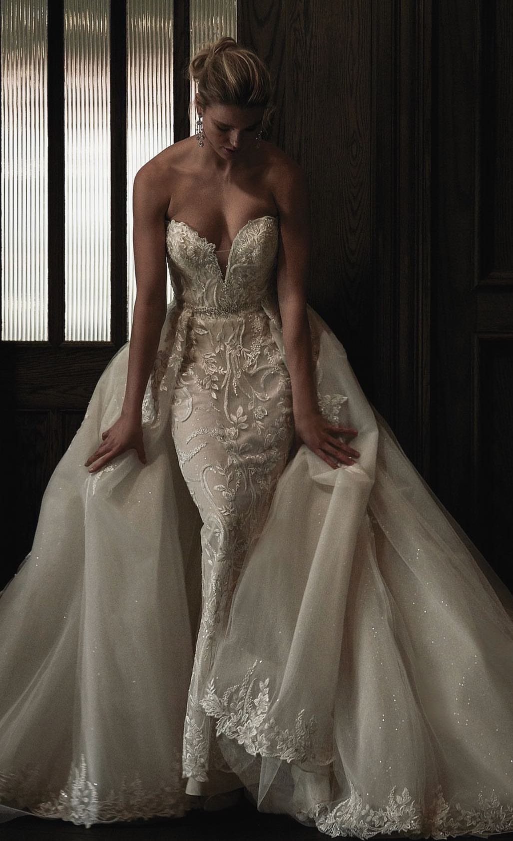 Woman in a strapless ivory wedding dress with lace embroidery and sparkling details.