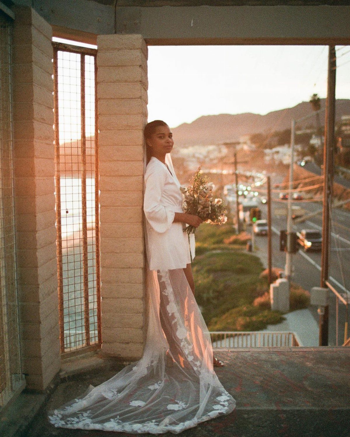 Woman in white lace bridal attire with a long train holding a bouquet