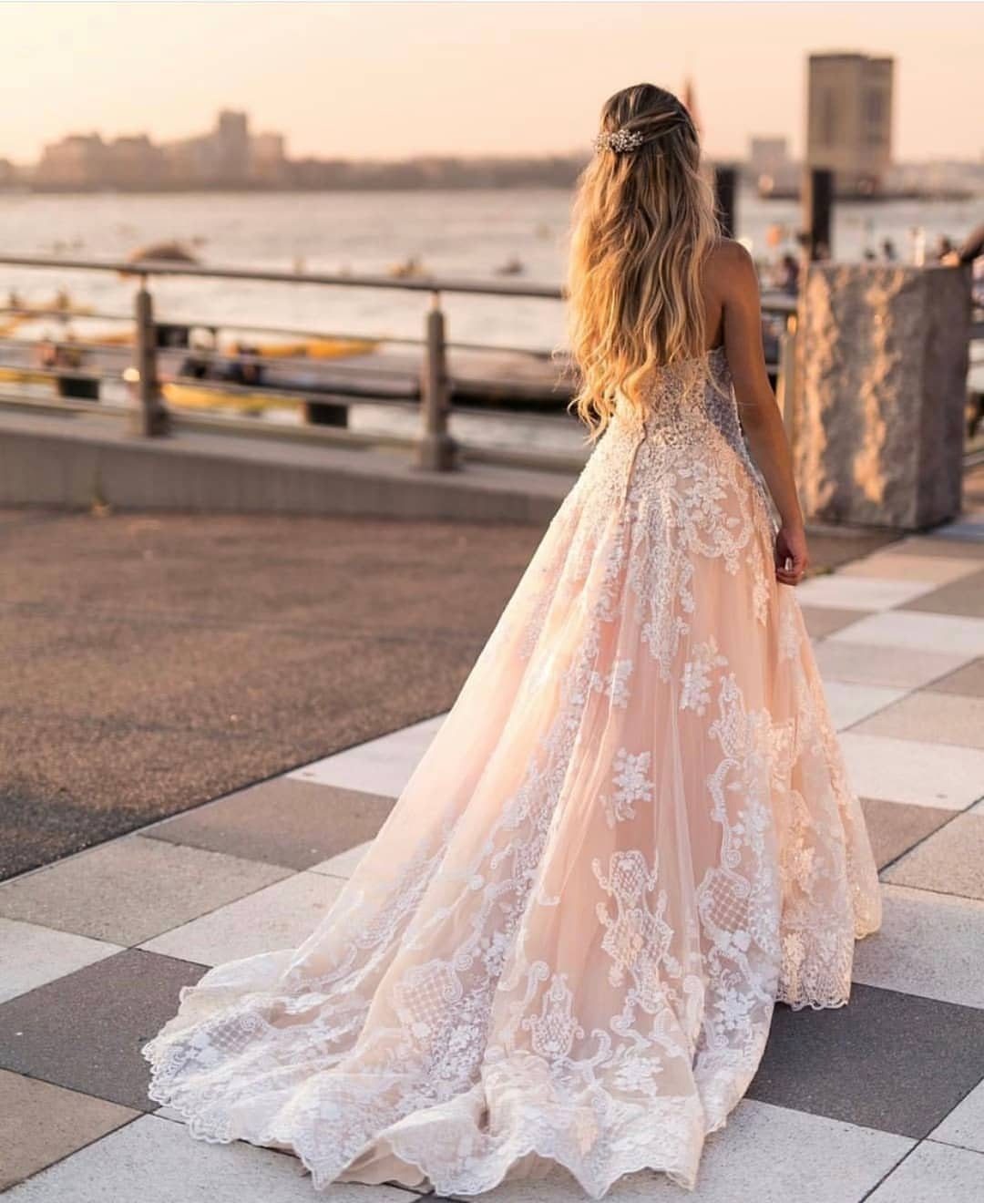 Woman in a peach and white lace A-line wedding dress on a waterfront