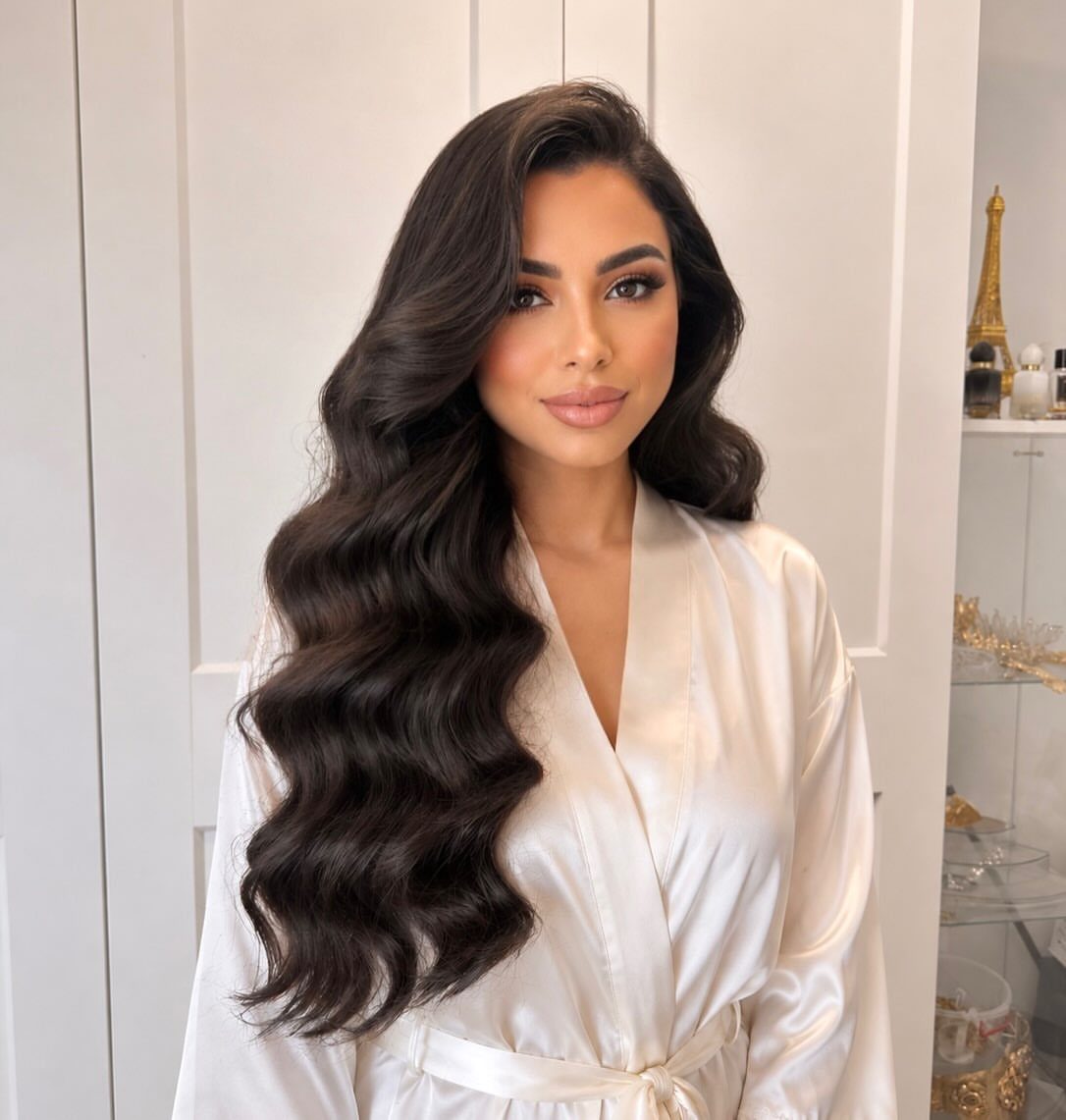 Woman with long dark brown cascading curls wearing a white satin robe