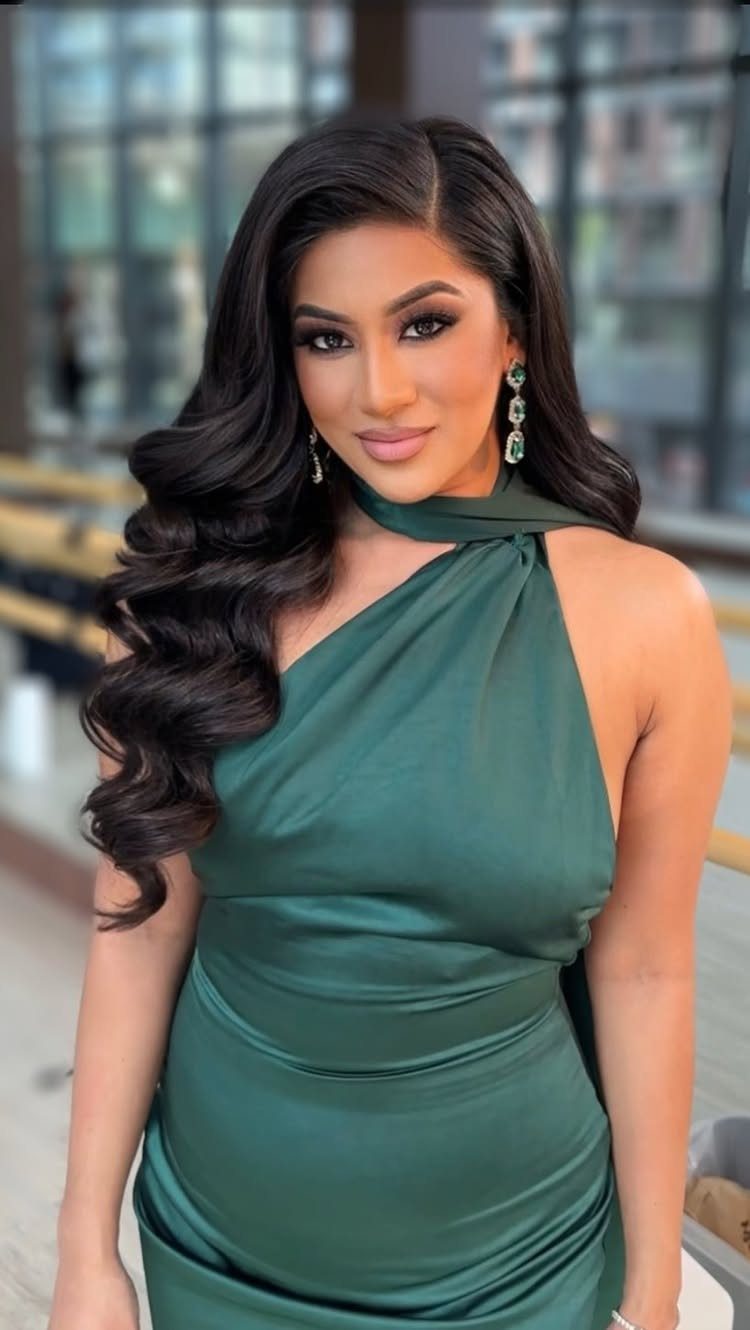 Woman with long dark hair in glamorous Hollywood waves wearing a green satin dress