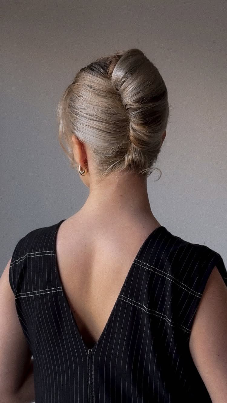 Blonde hair styled in a twisted updo on a woman wearing black pinstripes.