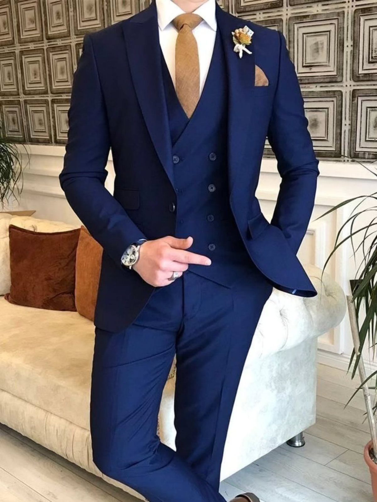 Man in a three-piece navy blue suit with a gold tie and white shirt.