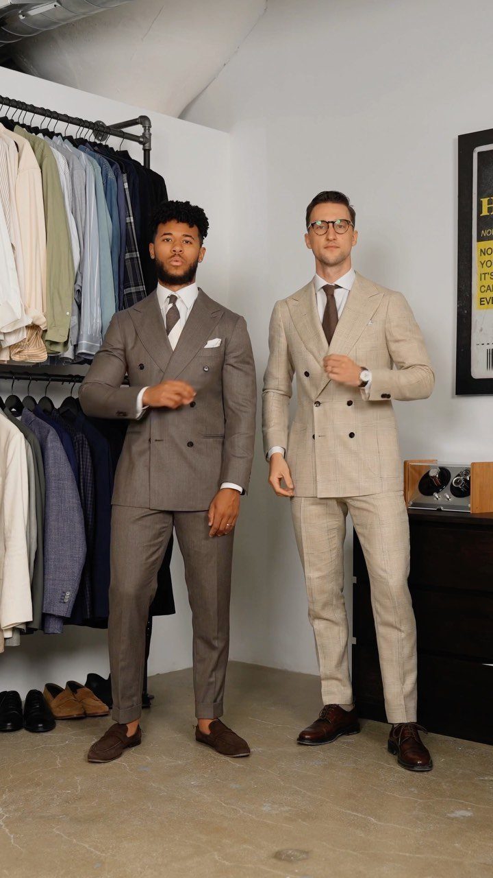 Two men posing in tailored grey and beige double-breasted suits in a boutique.