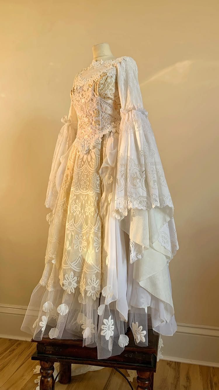Ornate cream wedding dress with lace and bell sleeves on a mannequin