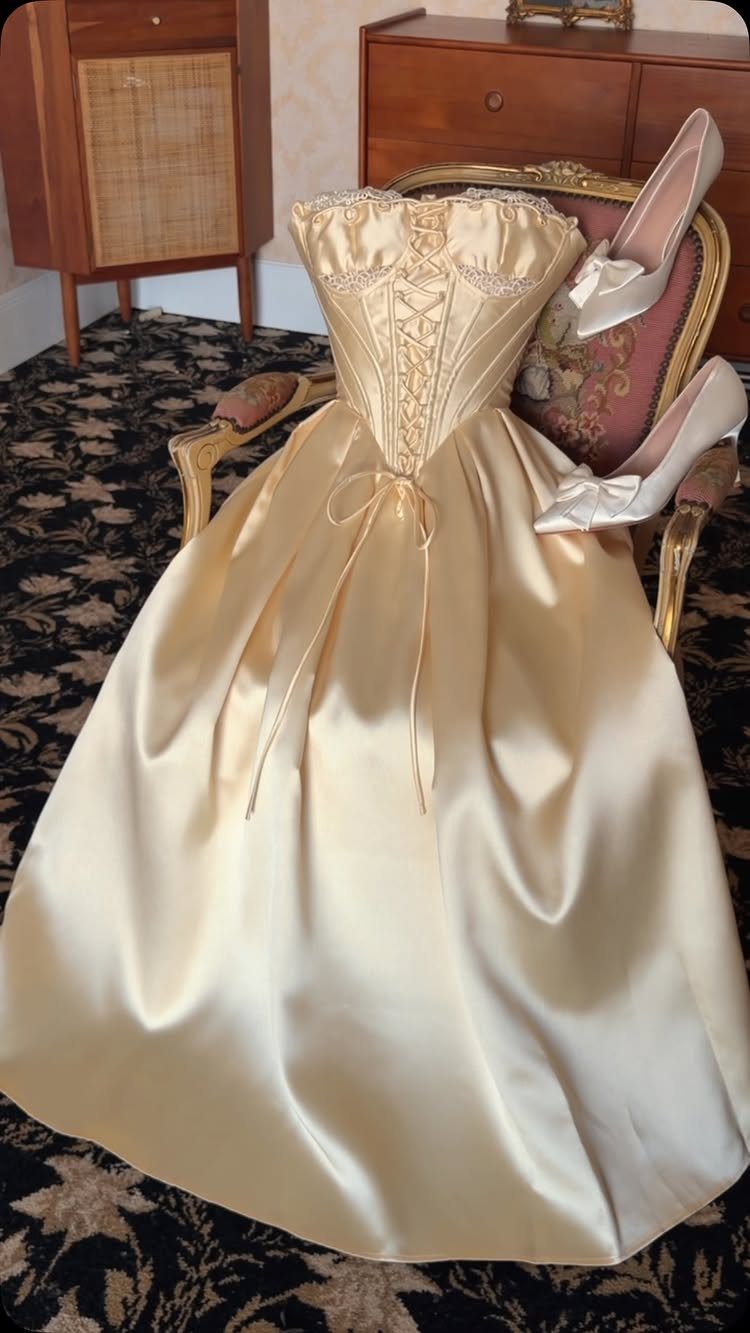 Cream satin wedding dress with corset bodice draped over a vintage chair