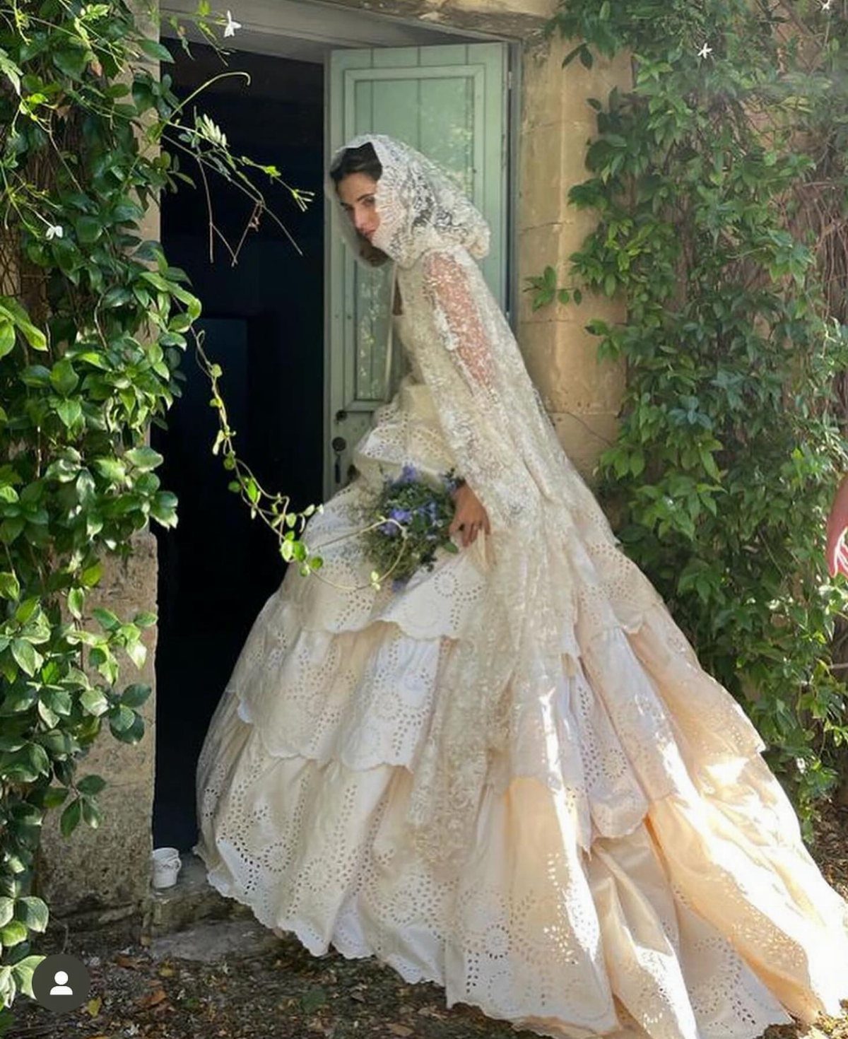 Woman in a tiered Victorian wedding dress with lace veil and sleeves