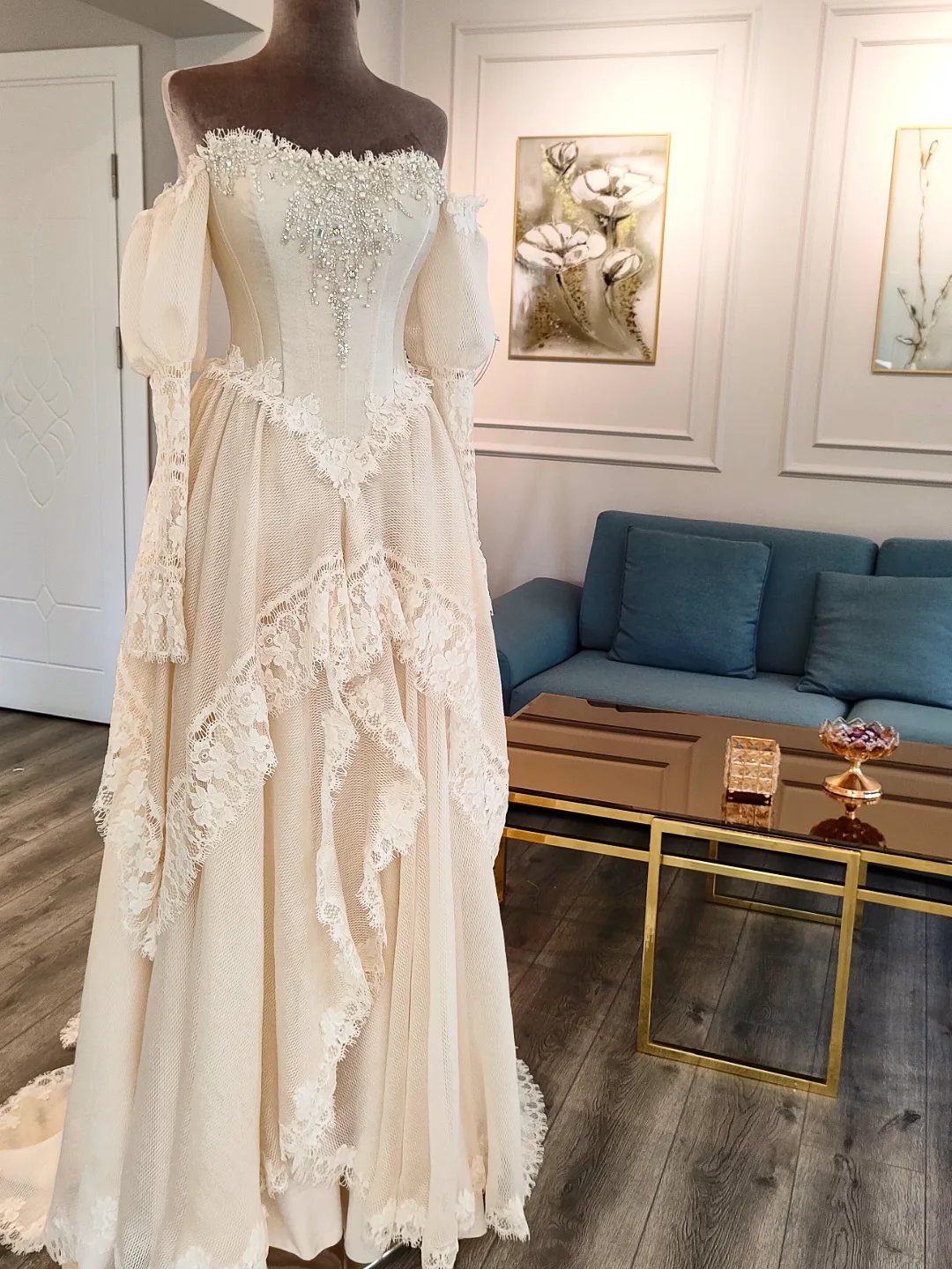 Cream vintage wedding dress with lace details and detached puff sleeves on mannequin