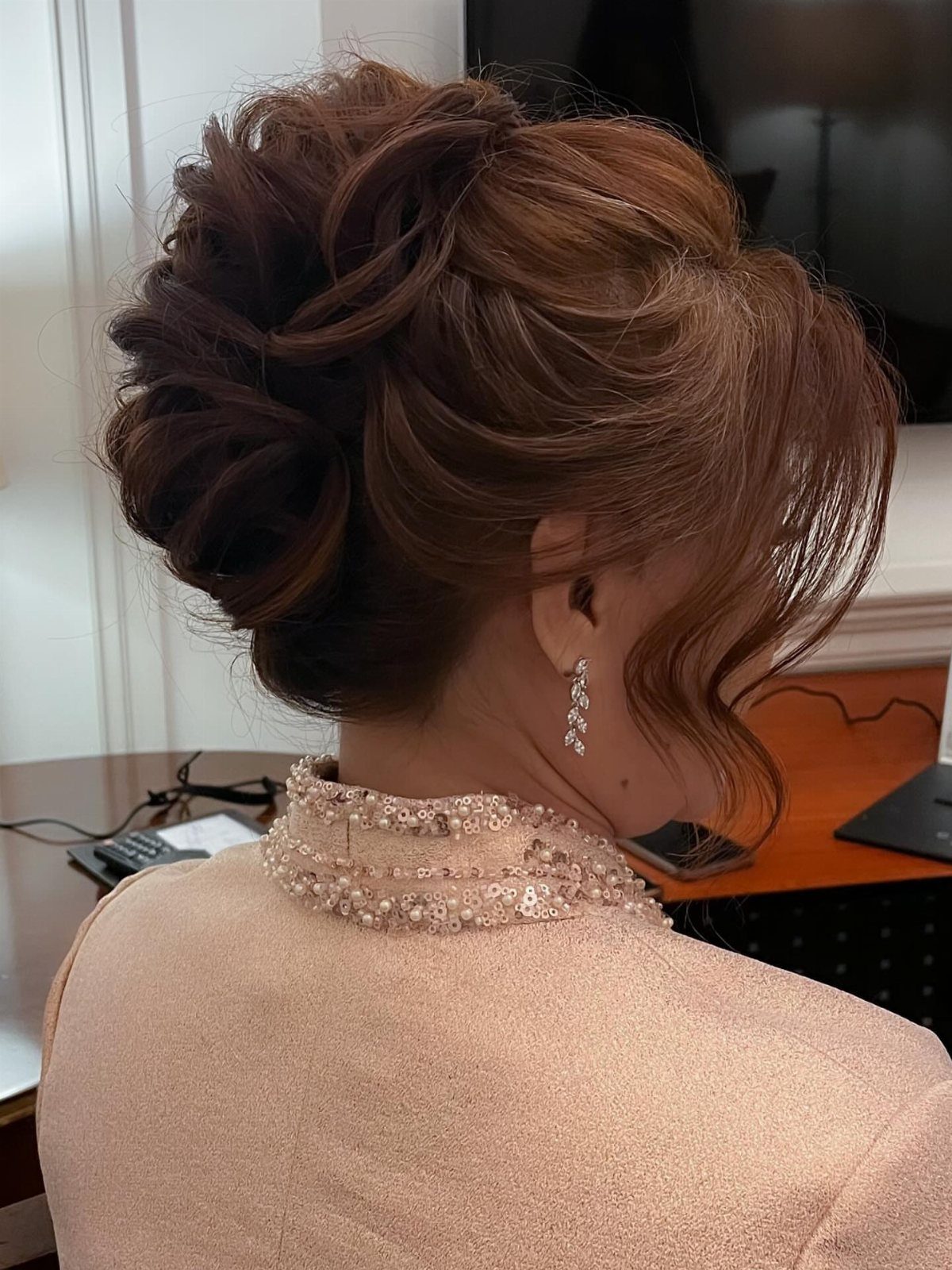 Woman with reddish-brown hair in an elegant low chignon and champagne dress.