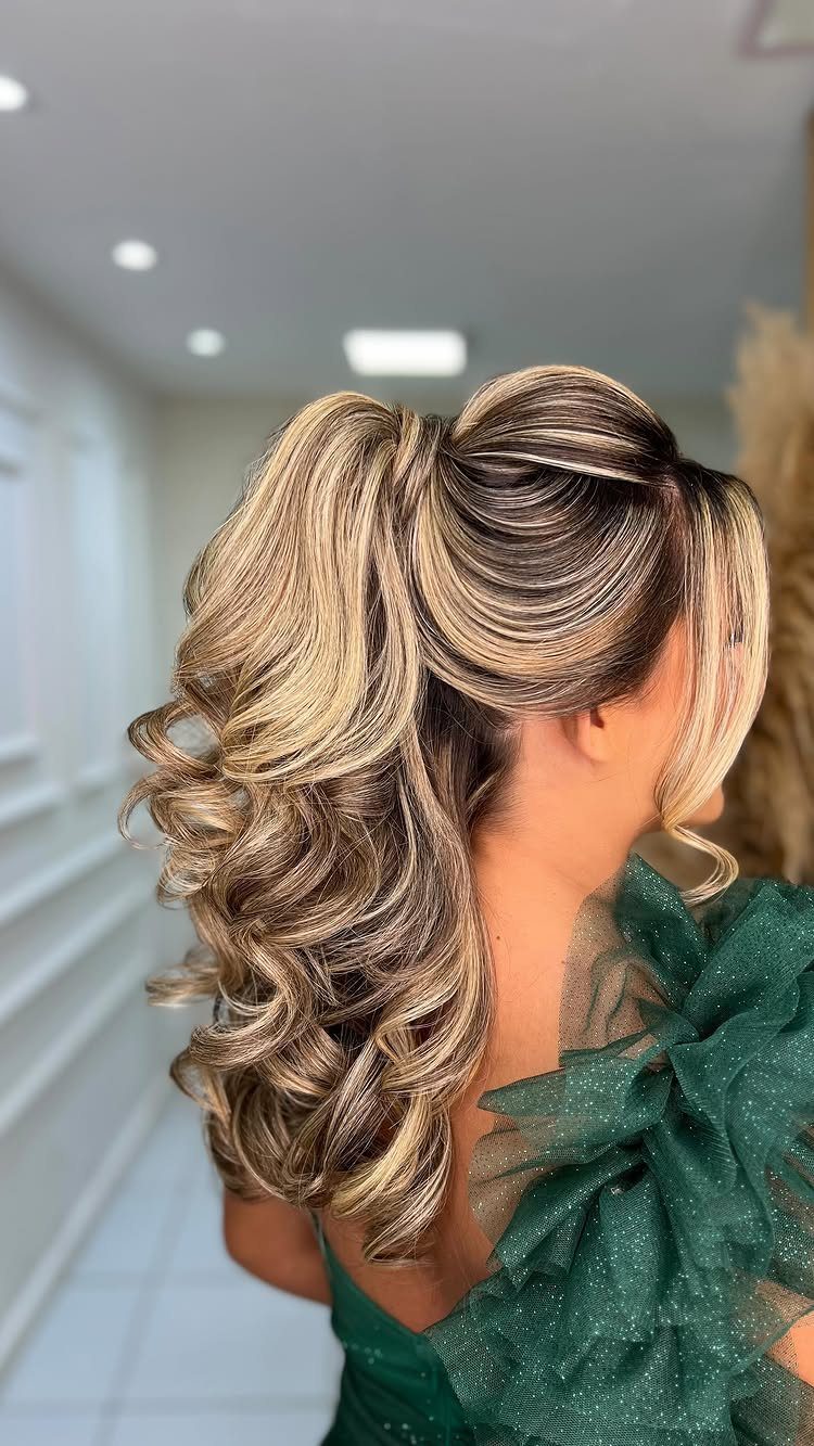 Woman with blonde highlighted hair in a curly high ponytail wearing green dress