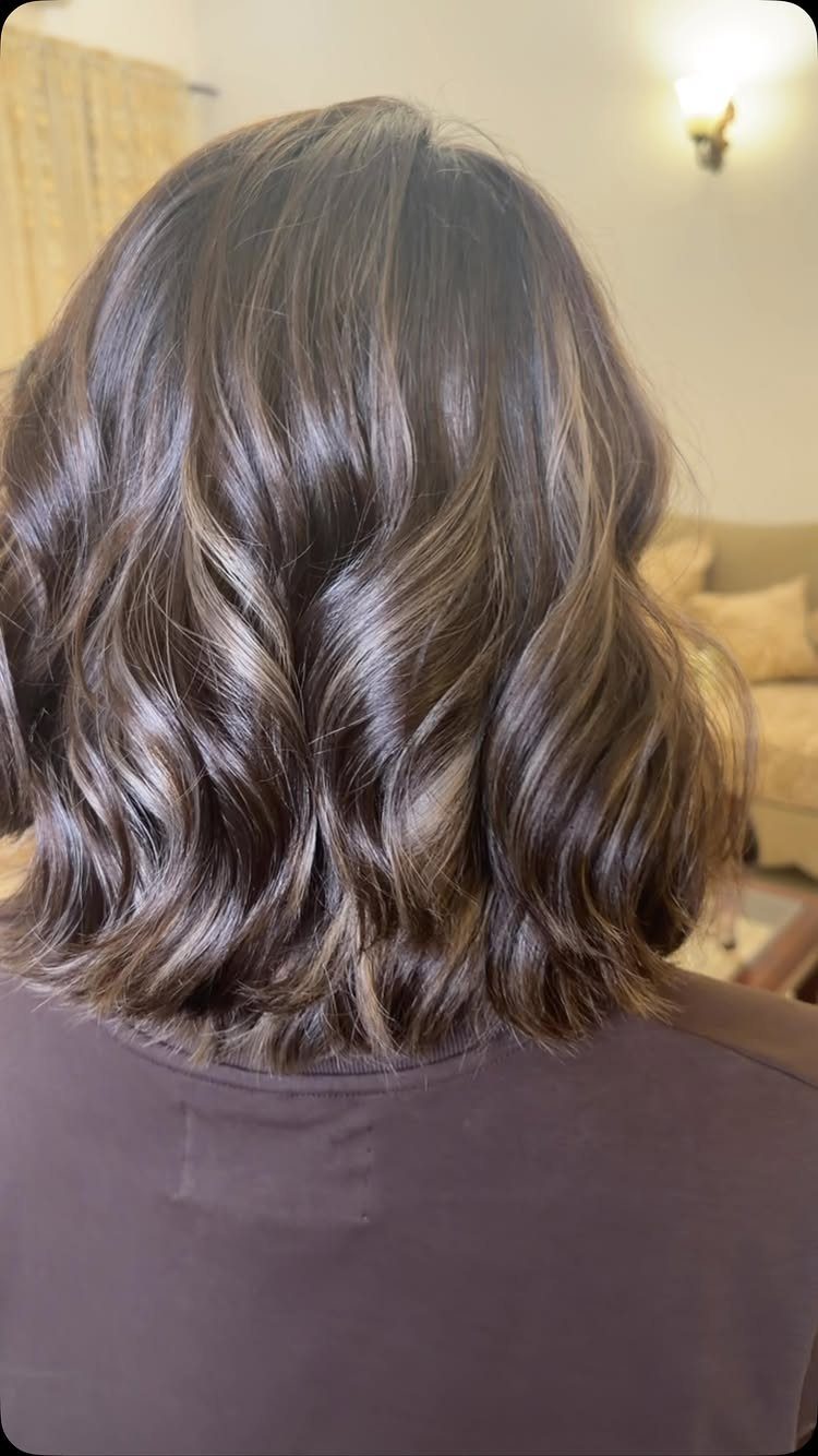 Shoulder-length brown hair styled in soft, voluminous waves seen from behind.