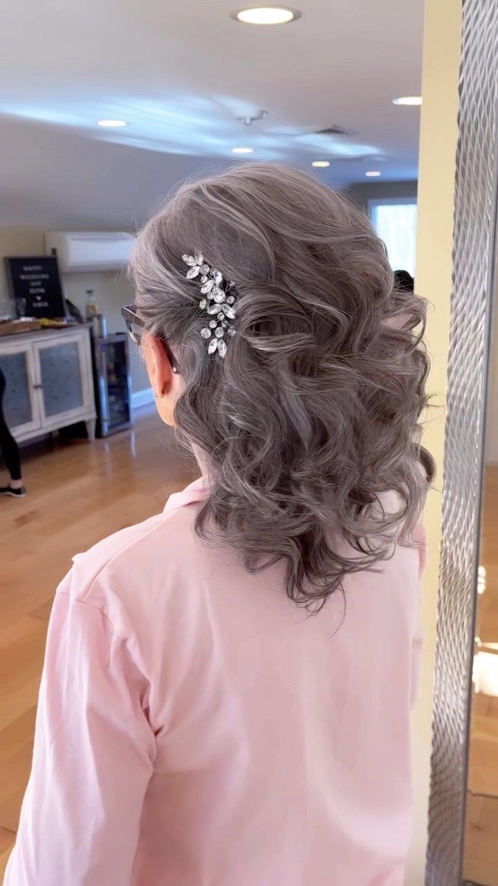 Wavy grey hair styled with a sparkling silver floral clip for a formal occasion.