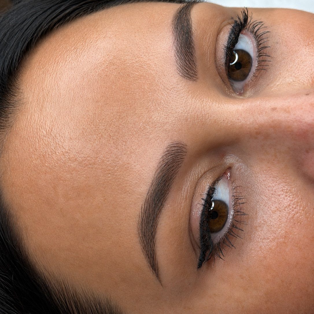 Close-up of a woman's face showing defined, groomed natural eyebrows and mascaraed lashes.