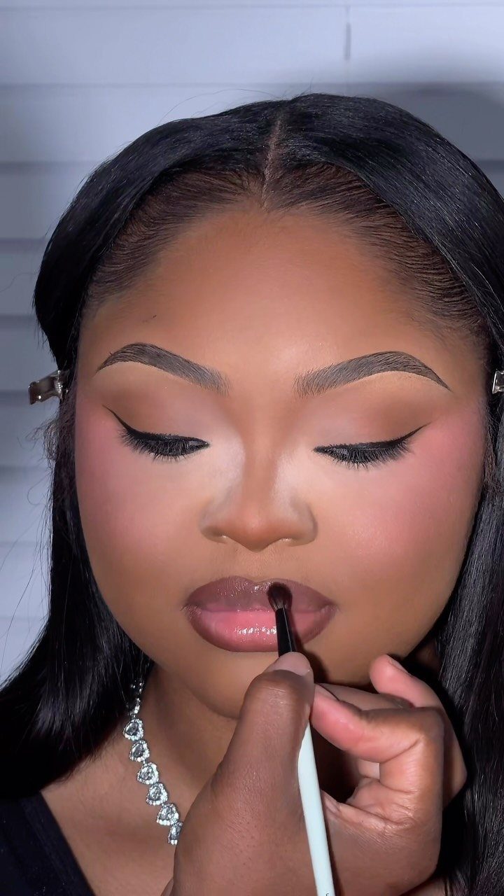 Woman receiving a makeup application with a focus on her lips and complexion.