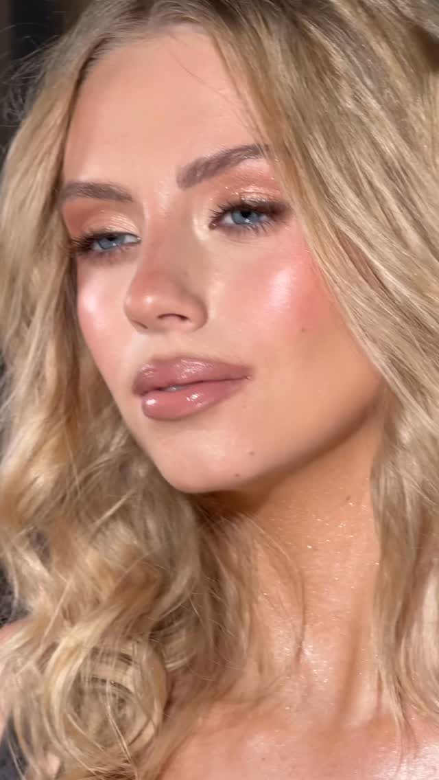 Woman with blonde hair wearing shimmering gold eyeshadow and glowing bridal makeup.
