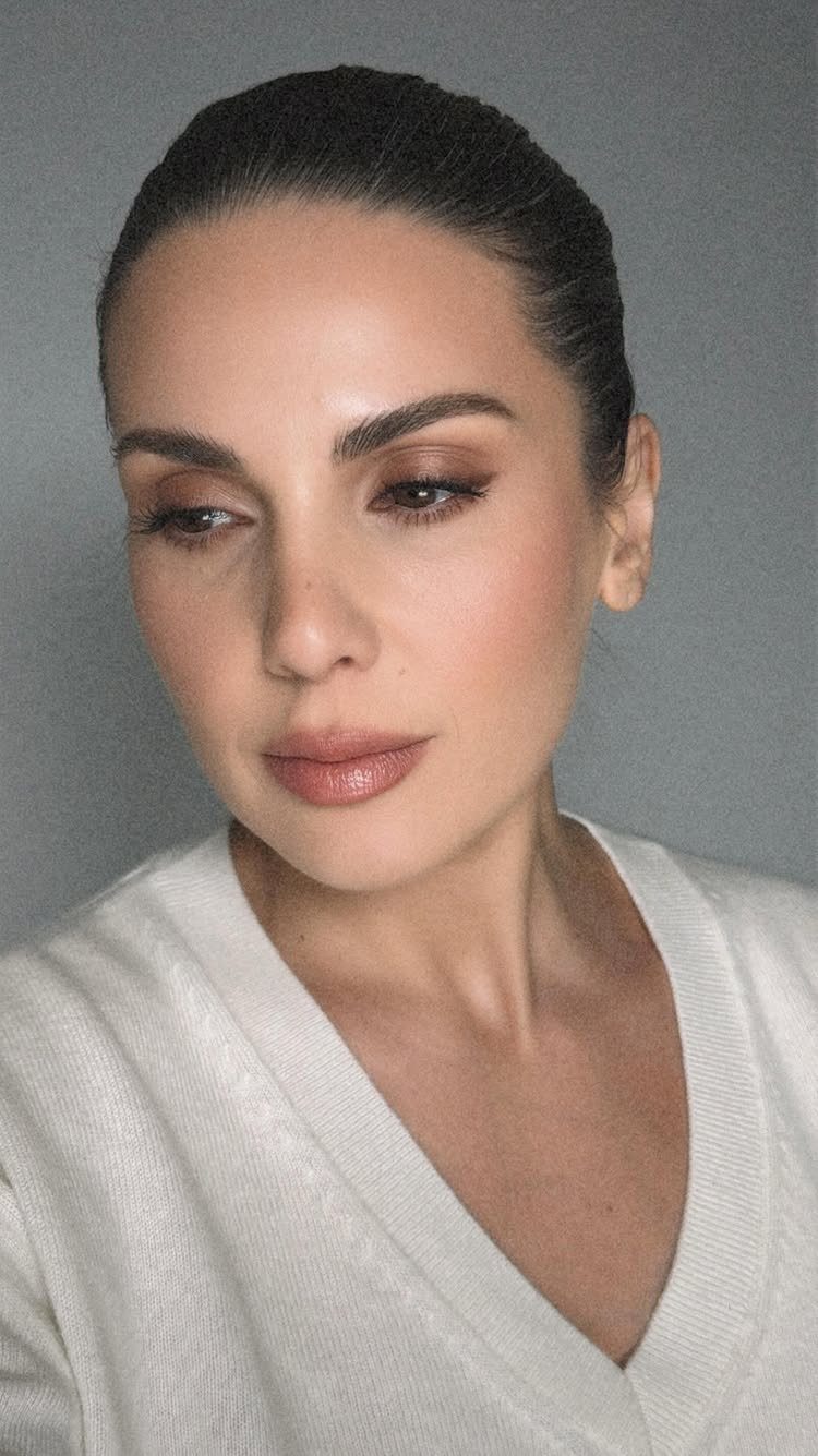 Woman with fair skin wearing natural neutral makeup and a white V-neck top.