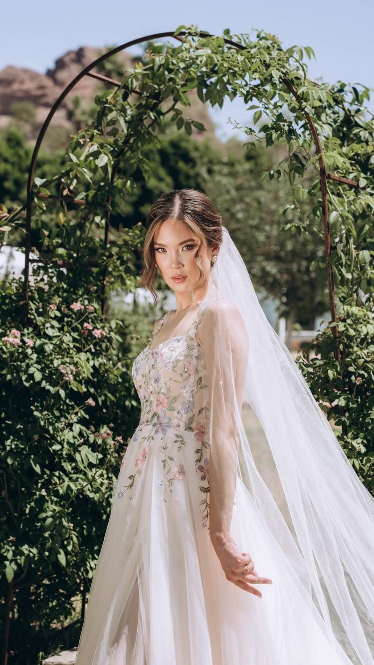 Woman in a white wedding dress with colorful floral embroidery and a long veil
