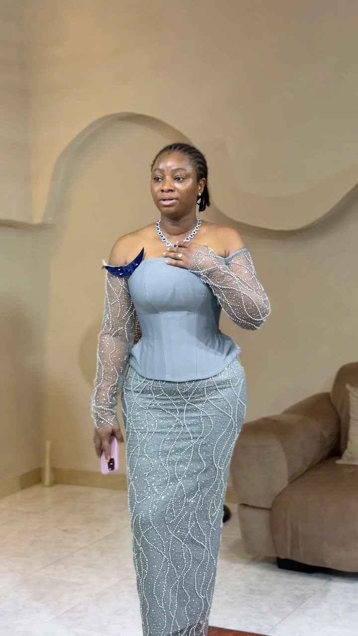 Woman in a light blue off-the-shoulder beaded gown standing in a living room