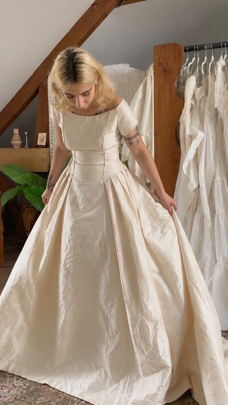 Woman wearing a cream-colored vintage-inspired wedding dress with a full satin skirt.
