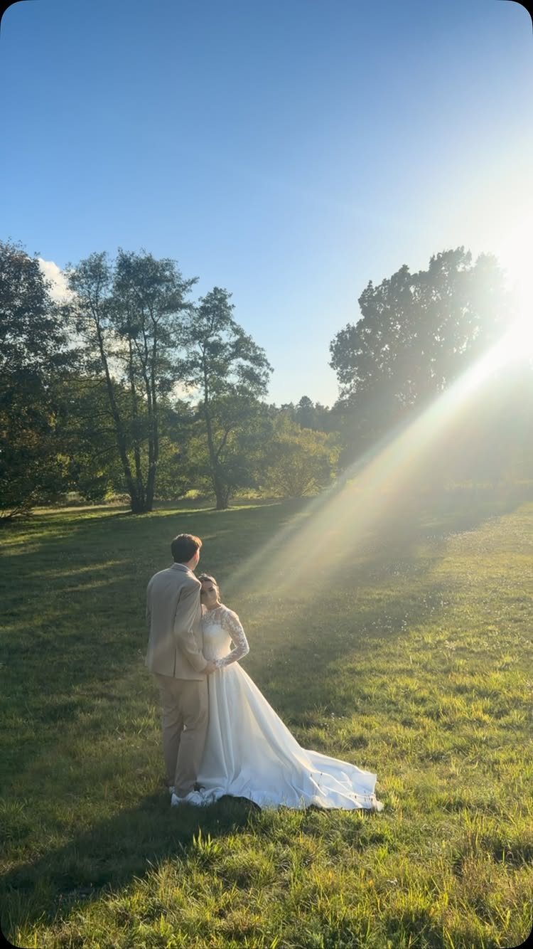 Man in beige suit and woman in white gown in sunny field