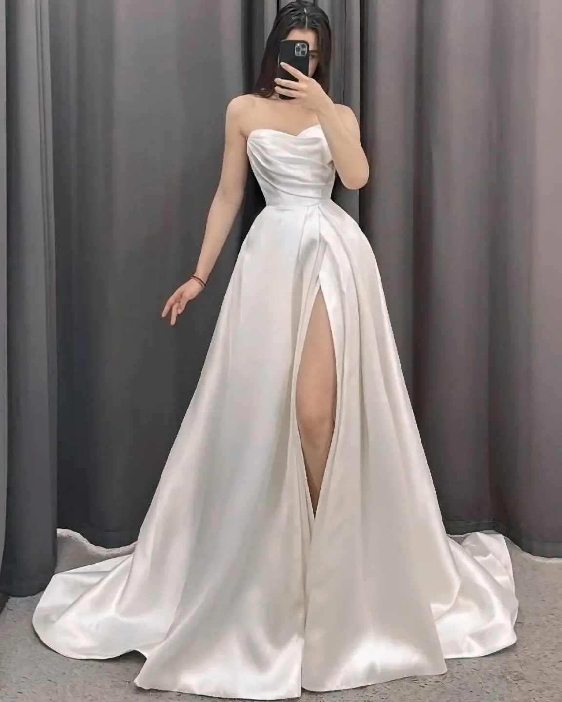 Woman in a white satin strapless wedding dress featuring a high leg slit.