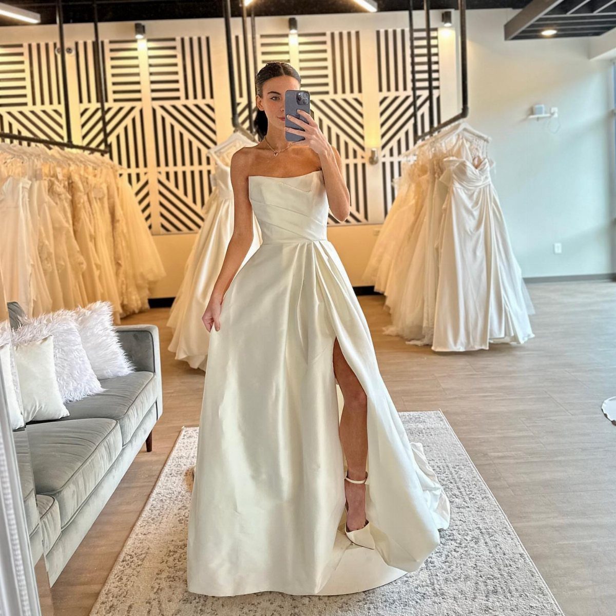 Woman in a white satin strapless wedding dress with a high leg slit.