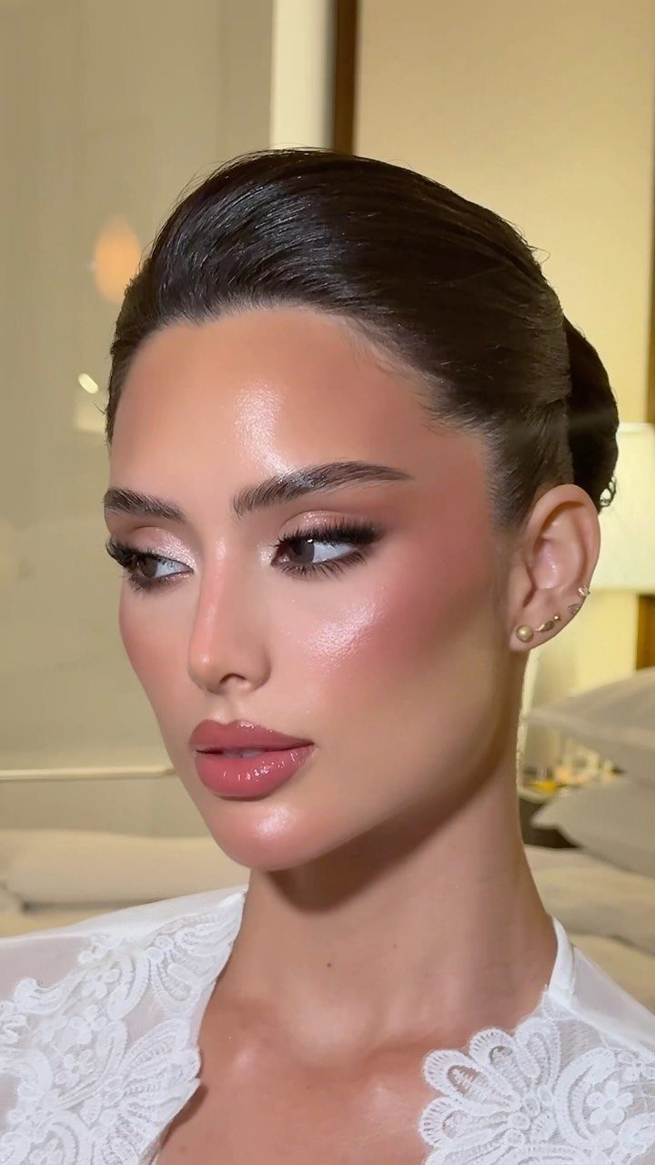 Woman with classic soft glam makeup and sleek bun wearing white lace.
