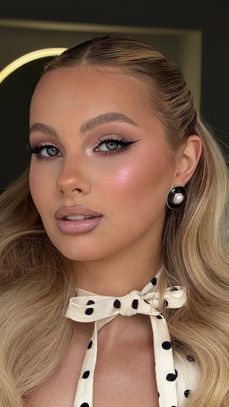 Woman with peachy shimmer eyeshadow, nude lips, and glowing skin for soft glam makeup.