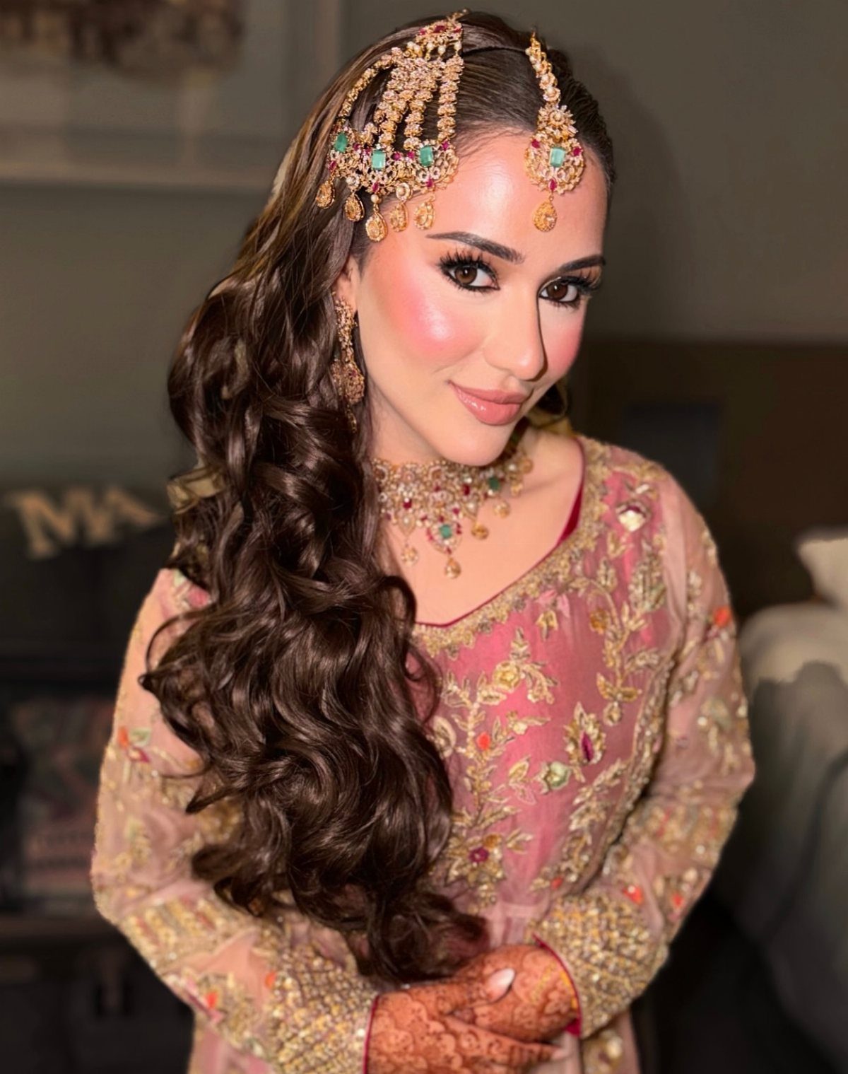 Woman in pink bridal attire with soft brown eyeshadow and gold jewelry