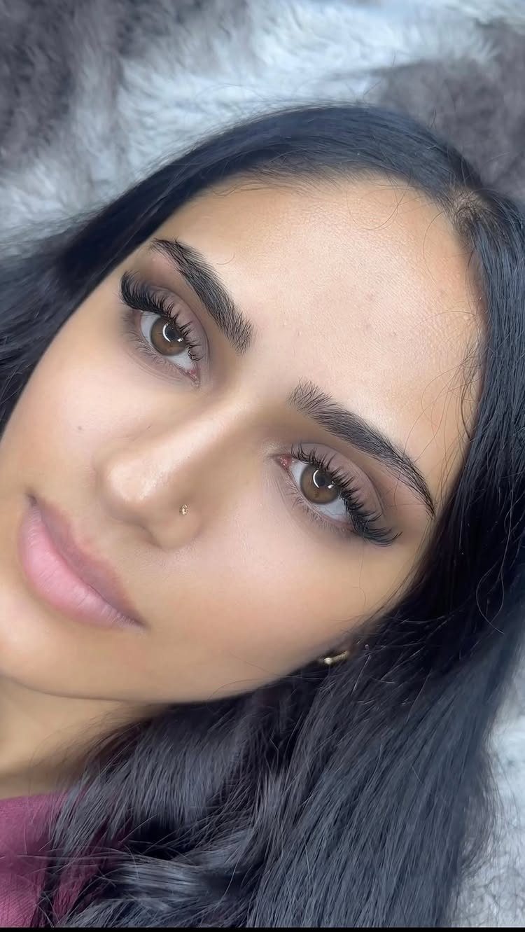 Woman with soft brown eyeshadow and long, fluttery false eyelashes posing for portrait.