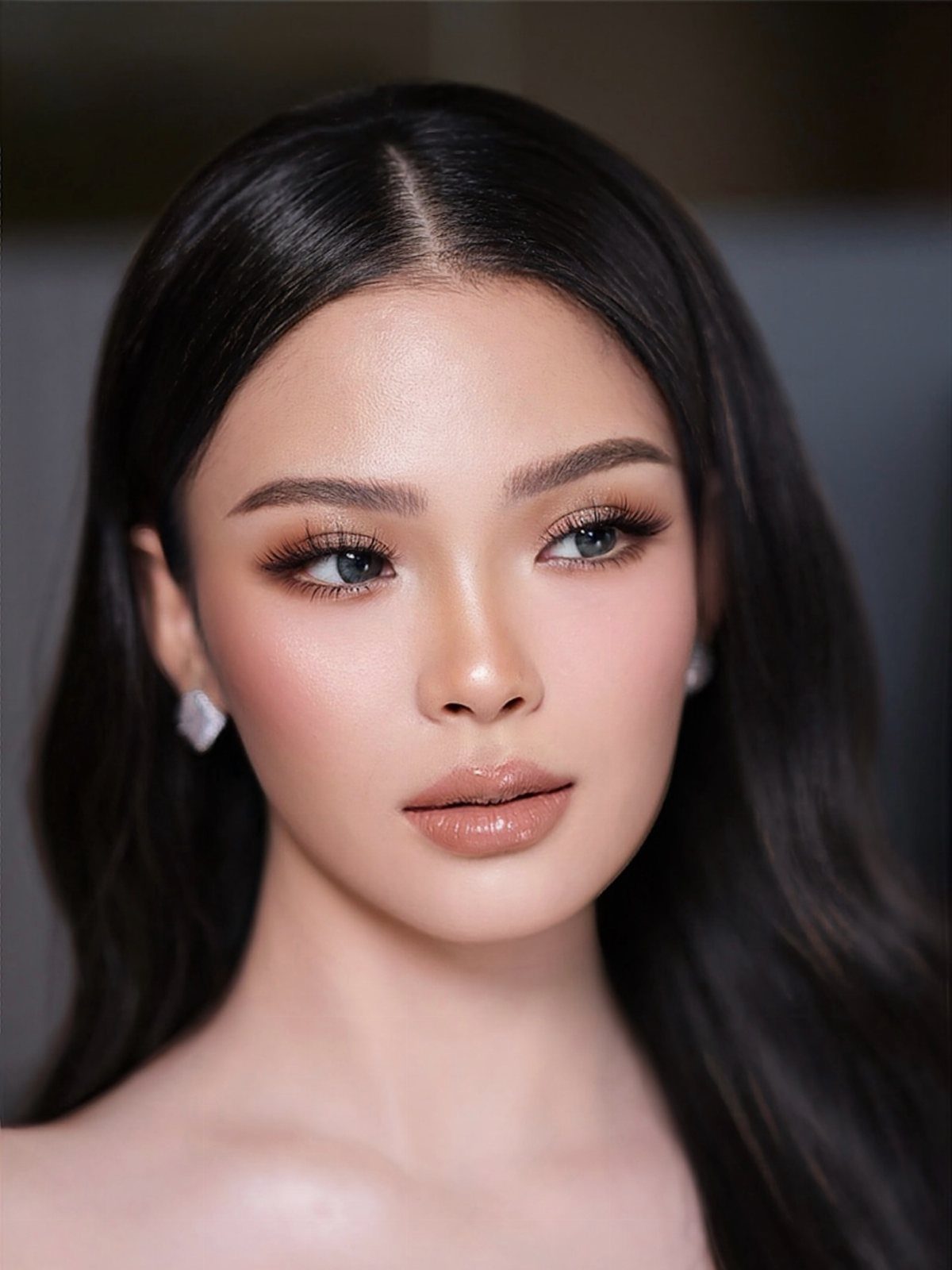 Woman with soft glam bridal makeup, defined eyes, and glossy nude lips.