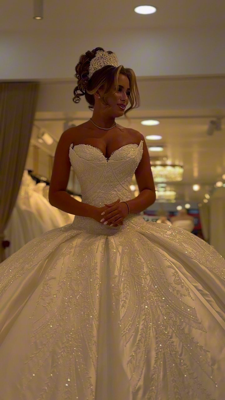 Woman in a voluminous white sparkly ball gown wedding dress wearing a tiara.