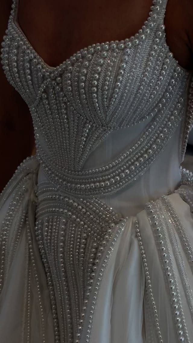 White wedding dress bodice and skirt decorated with intricate rows of white pearls.
