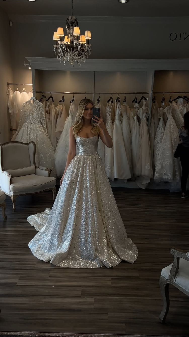 Woman in a shimmering sparkly silver-white wedding ball gown in a bridal boutique.